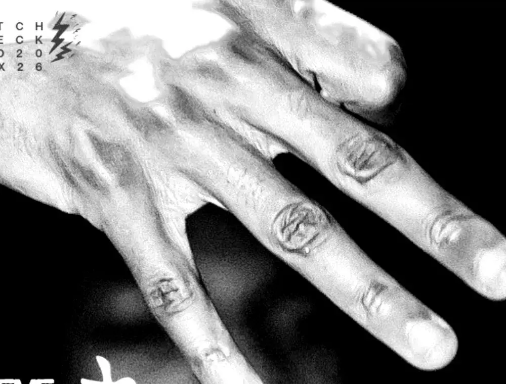 Mano tatuada cubriendo un rostro, retrato en blanco y negro.
